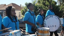 Drummers in blue polo shirts marching