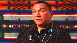 Headshot of a man with Native American designs in the background